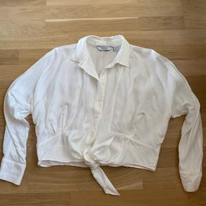 En jättefin vit lite kortare blus/skjorta med en liten knytning där fram och i nyskick (aldrig använd)
