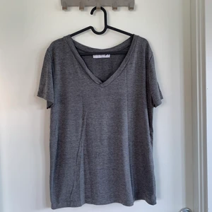 V-ringad T-shirt  - En grå V-ringad T-shirt med tunnare tyg. Ganska stor i modellen och passar upp till L skulle jag säga. Använd men som i nyskick. 