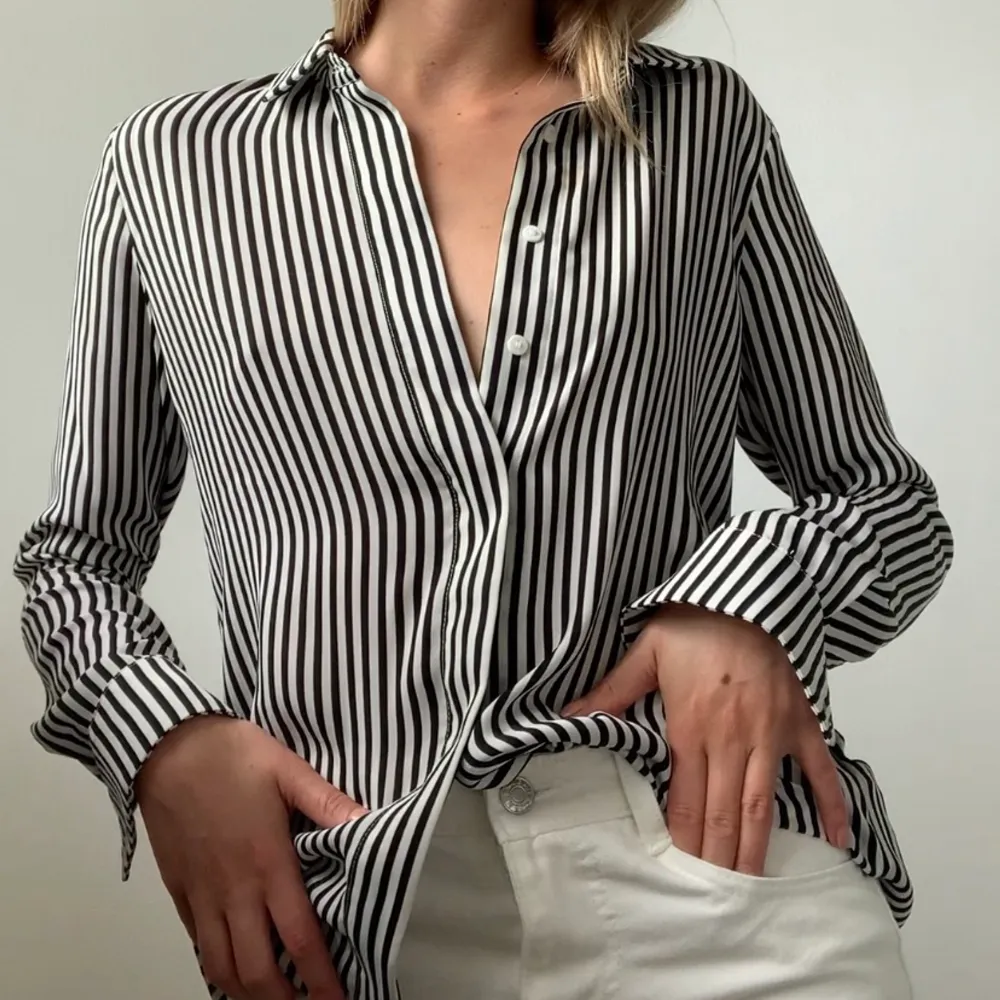 En tunn svart/vit randig skjorta från H&M i strl 34. Materialet är likt satin så det är lite blankt. I princip aldrig använd. FRAKT tillkommer från 66kr. . Blusar.