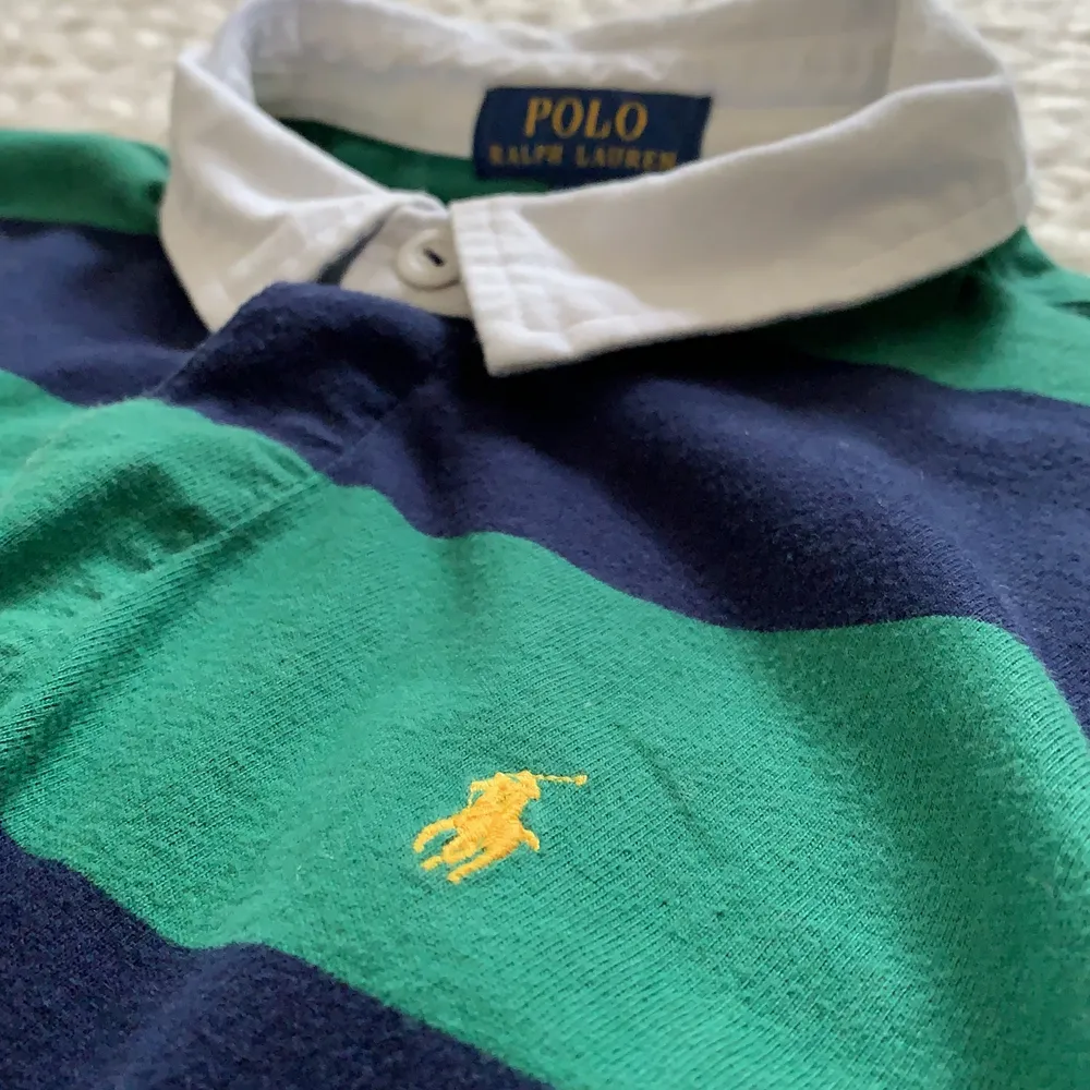 En Polo Ralph Lauren långarmad stl 164. Väldigt bra skick köpt på NK 2019. Den är blå och vit med ett gult tryck.. Tröjor & Koftor.