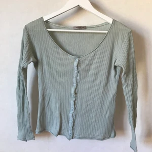 Söt tröja med knappar, XS-S - Den här är verkligen HELT underbar men jag måste tömma garderoben. Ribbad med fina detaljer och knappar. I en ljust turkos eller ljusblå färg och lagom kort i längden. Kan mötas i Stockholm eller skicka mot fraktkostnad! ✨🌸✨