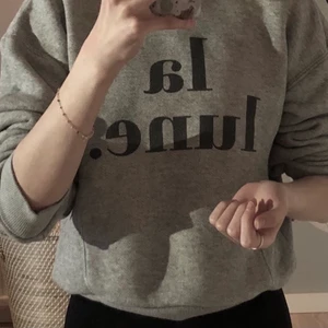 Grå tjocktröja med tryck från ginatricot - En cool grå tjocktröja med svart tryck där det står ”la lune”. Mysig, varm, med bra kvalitet. Storlek XS från ginatricot. Säljs eftersom den inte passar mig längre. Köptes för ca 300kr säljs nu för 169kr. 3 för 2!🧚🏻‍♀️