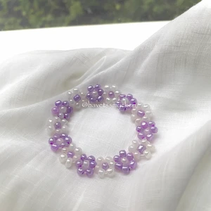 Skimrande pärlarmband  - Pärlarmband av skimrande glaspärlor i ljuslila och vit nyans. Perfekt att kombinera med andra smycken! Armbandet är ihopsatt med hållbar elastisk tråd och passar de flesta handleder.