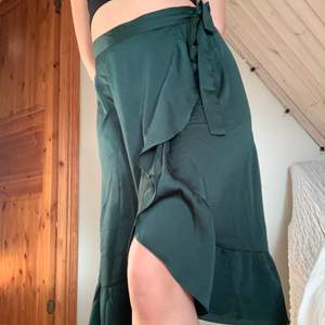 Medellång kjol i väldigt fin grön färg som dessutom är lite glansig vilket inte syns så bra på bilderna! Hittar ingen storlek men eftersom man knyter den omlott själv kan den passa både s och M!