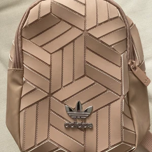 Adidas miniryggsäck - Söt liten ryggsäck från Adidas. Knappt använd och i väldigt fint skick! Fin gammelrosa/beigerosa färg. Gulligaste våraccessoaren!