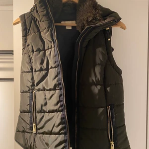 Grön väst - Säljer denna as snygga mörkgröna västen, perfekt nu till våren!! Har en mjuk pälskrage samt ett utfällbar luva. Passformen är figursydd!! Verkligen en så fin väst🧚🏼❤️