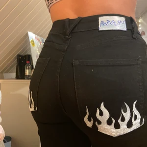 Jeans - Ett par svara skinny jeans med slits där nere med eld flammor på fickan