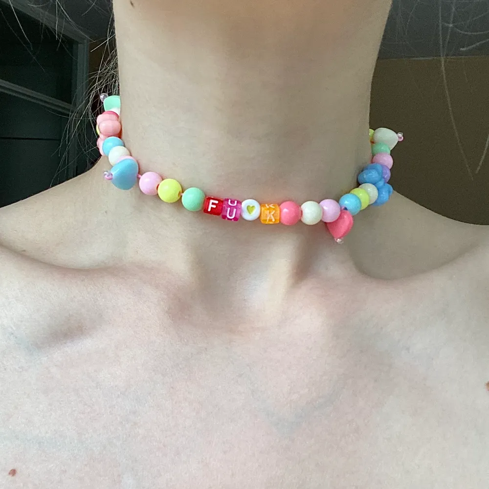 Pärlhalsband, typ choker, i barnslig stil med ”fuck” skrivet. . Accessoarer.