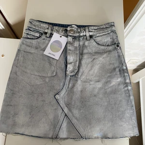 Silver Denim Skirt-Highwaisted - Kjolen är köpt ifrån Monki och har fortfarande prislappen på! Satt alldeles för tight på mig då jeansmaterialet INTE är stretch. Aldrig använd då mina höfter inte får plats i kjolen🥲 Skit snygg och den reflekterar ljus!💗💗kort kjol!