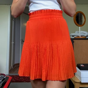 Orange pilsserad kjol - Orange mini/midi kjol från H&M. Den är anpassningsbar med resår i midjan. Perfekt kjol på sommaren! Använd ental gånger. Köparen står för frakten:)
