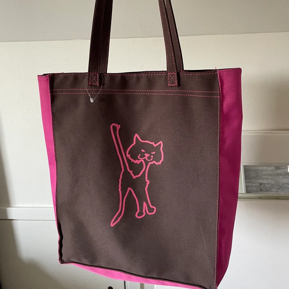 Brun/ rosa vintage tygväska i toppskick! 💘 Passar till precis allt och färgerna gör att det blir en 2000s vibe samt look!! Riktigt unik och cool, med en katt på. Finns dragkedja både bak och inuti. Väskan själv stängs också mha en dragkedja. . Väskor.
