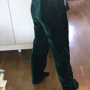 Velvet kostymbyxor - Mjuka gröna kostymbyxor som är vida i benen. Sista bilden visar lite mer hur de faktiskt ser ut i färgen. Dragkedja o fickor finns <3Aldrig använda. Köparen står för frakten💚