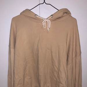 Hoodie - En beige hoodie från Bik Bok som knyts där nere.