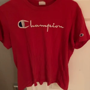 Röd champion t-shirt - Röd t-shirt från champion. Det sydda märket är lite skadat som man ser på den tredje bilden. Storlek M