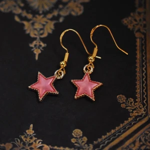Örhängen med rosa stjärnor  - Handgjorda örhängen med guldpläterad berlock och nickelfria krokar 🌙 På min profil finns fler örhängen med berlocker i flera andra storlekar, färger och former! 🪐 Köp 1 par för 40kr, 2 par för 70kr, 3 par för 100kr! Örhängena levereras i en fin liten presentpåse. Frakt på 13kr tillkommer 💫