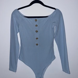 Baby blå body - Baby blå body från Boohoo med knappar längs brösten. Använd 2 gånger. Köpte den för ungefär 1 och ett halvt år sedan. Jättefin att ha på t.ex fest eller middag🤍