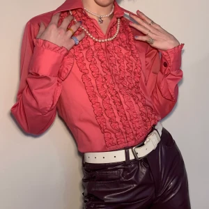 Rosa vintage 70s skjorta med volang och krås Harry styles liknande - Rosa äkta vintage 70s skjorta med krås på bröstet samt volanger längst ser på ärmarna 🌺 Tröjan påminner så mycket om Harry Styles både stilmässigt men även färgmässigt! För att få en snygg kontrast kan man stylea den med ett par skinnbyxor och ett par kängor eller för en mer casual look med jeans och ett linne under samt ett par matchande sneakers! Storleken är inte given men jag skulle säga att det är en M-L men kan va såå snygg som en oversized S!