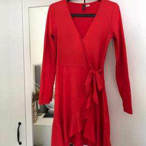 Röd omlottklänning med fin v-ringning från H&M, fint skick, endast använd fåtal gånger. Knyte runt midjan och knapp upptill. Fin klarröd färg. 