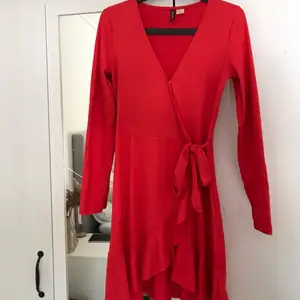 Röd omlottklänning med fin v-ringning från H&M, fint skick, endast använd fåtal gånger. Knyte runt midjan och knapp upptill. Fin klarröd färg. 