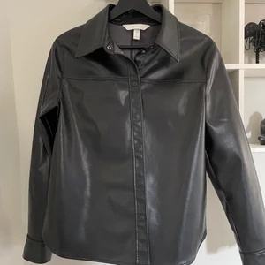 Skinnskjorta - ”Skinn”skjora från H&M, inte äkta skinn. Använd en gång. Säljer pga kommer inte till användning! Storlek 38 men jag anser att den nästan är mer som en 36a.