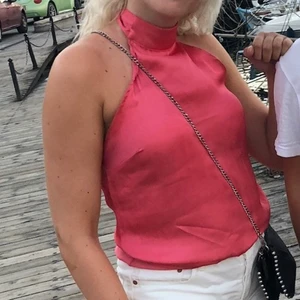 Rosa halterneck topp  - Halterneck topp som man knyter i nacken men långa band. Är i satin material men är 100% polyester. Har en liten fläck som jag inte får bort men den syns knappast. Annars i bra skick. KÖPAREN STÅR FÖR FRAKTEN!