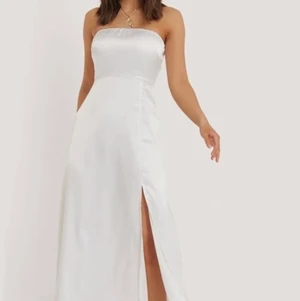 Vit Balklänning maxikläning  - Hej! Säljer en jätte fin vit balklänning /maxiklänning i Bandåmodell / bandeaumodell med en slits som gör att man kan röra sig fritt i klänning. Jätte fint matrial. Den har resår så den sätter sig jätte fint efter kroppen. Den är i st 38 från NAKD. Ny pris 500kr❤️