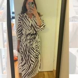 Klänning med slits  - En superskön och fin skjortklänning från Lindex, i storlek XS. Den sitter inte tajt i midjan, utan jag har lagt till ett skärp, den har slits på bägge sidor vid benen och färgen är mer vit och vinröd i verkligheten. Skriv ifall mer bilder önskas, aldrig använd!💖