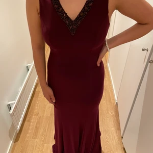 Vinröd klänning med detaljer , V-ringad - Säljer en V-ringad vinröd festklänning som endast är använd en gång. Säljer pga att den tyvärr blivit för liten. Klänningen passar S/36. Priset går att diskutera! 