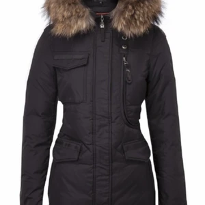 Hollies Livingo vinterdunjacka - Dunjacka Livigno från Hollies. Den har en stor pälskrage av äkta päls som sitter på huven. Denna modell har ett ”sportigare” utseende än de andra Hollies-jackorna. Figursydd, man kan spänna i midjan. Livigno har två framfickor med lock och två blixtlåsfickor ovanpå. Till höger finns en bröstficka med en knapp som stängs. En stor bröstficka på vänster sida öppnas med dragkedja.   Endast använd vintern 2020-2021, alltså bara några månader. Inga hål eller skavanker på den. Snabb affär prioriteras, 