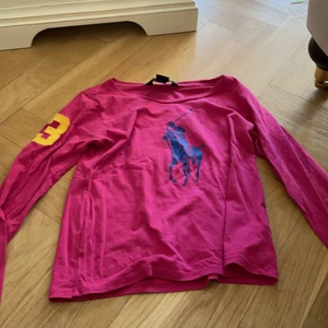 Ralph lauren  - En mörk rosa tröja med en 3 bak på ryggen.