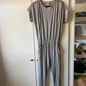 Grå byxdress  - Bekväm byxdress att bara ha hemma eller när man ska ut. Fina spetsdetaljer som pryder axlarna