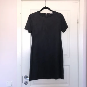 Svart klänning i fuskmocka  - Svart klänning i fuskmocka med silverdragkedja baktill. Fin passform med stretch. Går till strax ovanför knäna på mig (169cm). I mycket fint skick, endast använd ett fåtal gånger. 