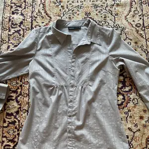 Figursydd grå/silver-randig skjorta med en väldigt smickrande passform!                                     Storlek 42                                            Material: polyester, bomull och elstan 