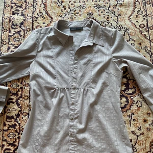 Figursydd skjorta storlek 42  - Figursydd grå/silver-randig skjorta med en väldigt smickrande passform!                                     Storlek 42                                            Material: polyester, bomull och elstan 