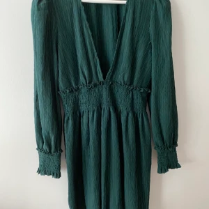 NA-KD Klänning - Mörkgrön NA-KD klänning med djup urringning framtill! Stretch runt midja! I storlek 38 men passar även större