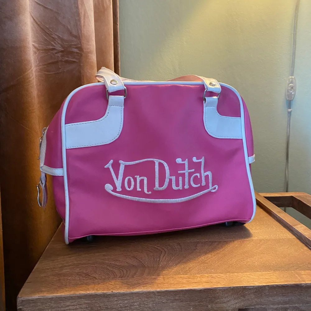 Säljer min underbart fina rosa von dutch väska som är extremt y2k!! Den är använd men i bra skick, det som skulle vara isf är att den skiftar lite från det vita på dragkedjan(kan skicka fler bilder)!! Fraktar men köparen står för frakt💕💕. Väskor.