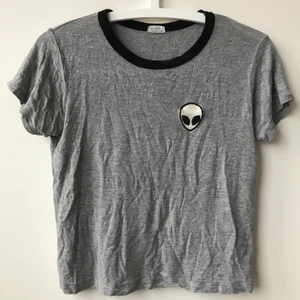 Kort t-shirt med alien-märke - Kort t-tröja, går ungefär till början av byxorna på mig. Storlek  XS ungefär. 