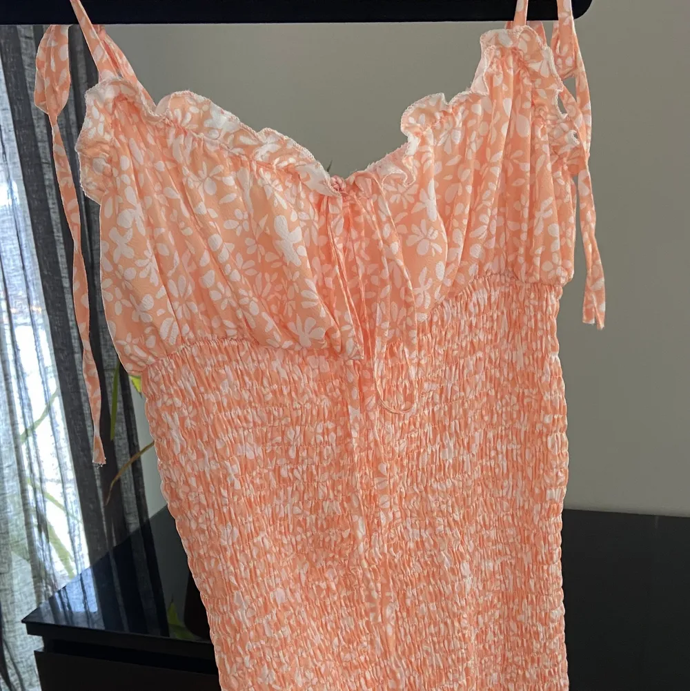 Fin klänning i smock med blommigt mönster persikofärg. Använd ca 3 ggr. Fint skick. Säljer då den är lite stor på mig. Strl M. Hämtas i Segeltorp eller postas mot fraktkostnad . Klänningar.