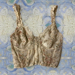 Blommig korsett - En blommig korsett topp av tunt tyg, lite genomskinligt. Är i storlek L men skulle säga att den är mer M/L däremellan. Aldrig använd, endast testad. Frakten ingår i priset.