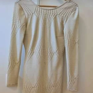 Klänning med detaljer strl S. - Kort figursydd festklänning köpt från en känd festklädes butik utomlands med lång ärm och öppen rygg med gulddetaljer i strl S som är använd vid ett tillfälle.