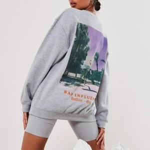 Grå sweatshirt  - Grå sweatshirt från Missguided med tryck baktill.  Köpt förra året men kommer tyvärr inte till användning längre. Frakt tillkommer.