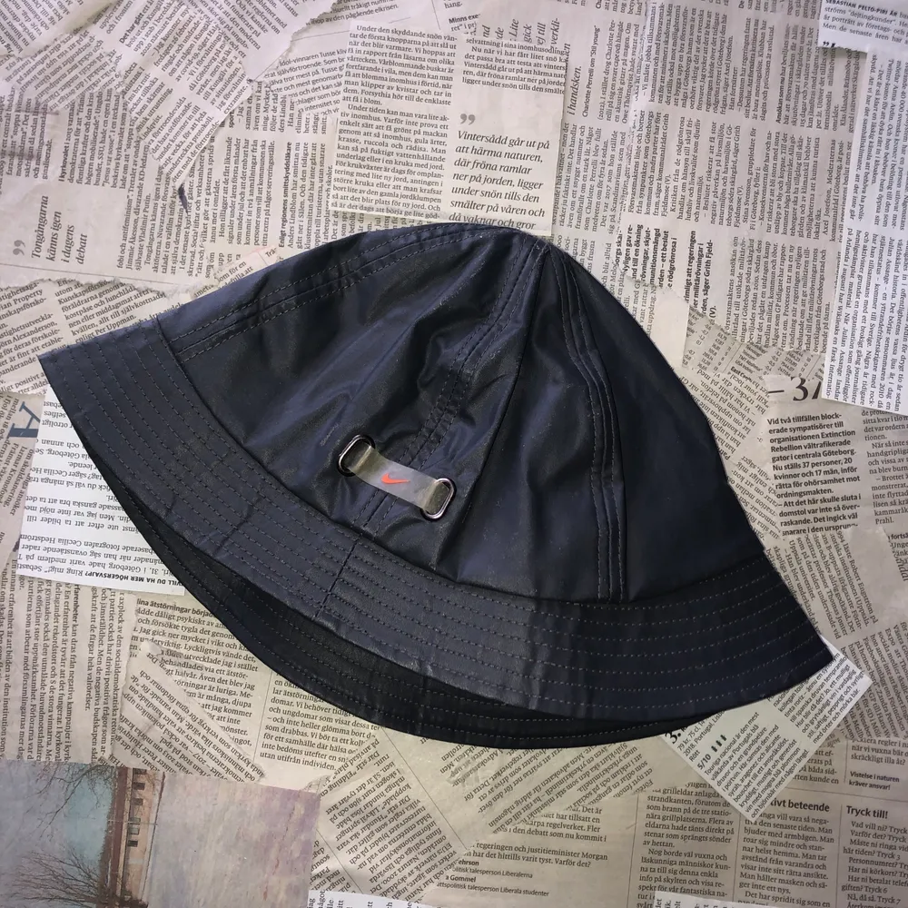 Riktigt cool buckethat i ett galoonliknande material (regntät) i mörkgrått med ett oranget swooshmärke, använd fåtal ggr. Accessoarer.