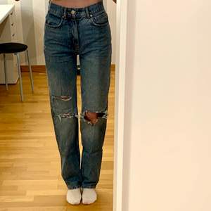 Blå jeans med hål på knäna i en 90-tals modell från gina tricot. Säljer då jag inte använder dem längre. Jag är 172 cm. Köpare står för frakt.