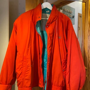 Retro jacka/skidjacka - Röd retro jacka som jag haft när jag åkt snowboard, används inte lika mycket längre tyvär, den är fodrad, storlek står inte men jag är 167 cm lång o den går precis över rumpan på mig skulle uppskatta storlek till S/M 