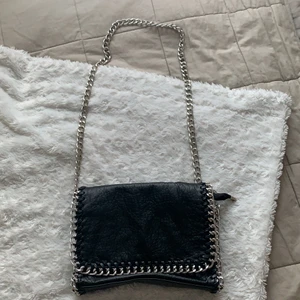 TIAMO Priscilla väska M svart - Axelremsväska med Fake skinn, ett fack med dragkedja på insidan och ett på utsidan. Även Två öppna fack på insidan. Längd 28cm, höjd 18 cm och 5 cm bred. Axellänken är 105cm. Väskan är i mycket fint skick. Alla dragkedjor är fungerande. Du står för frakten, ny kostar väskan 499kr☺️🖤