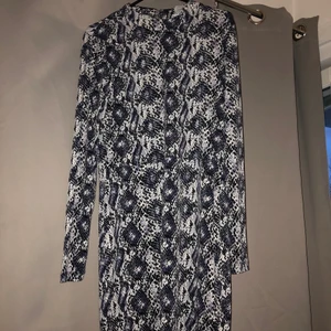 Ormskinnsmönstrad festklänning - Festklänning från H&M som aldrig använts! Har legat i min garderob i ett par år och nu känner jag att någon annan kan få ha den istället :) Möts i Gbg, annars står köpare för frakten.