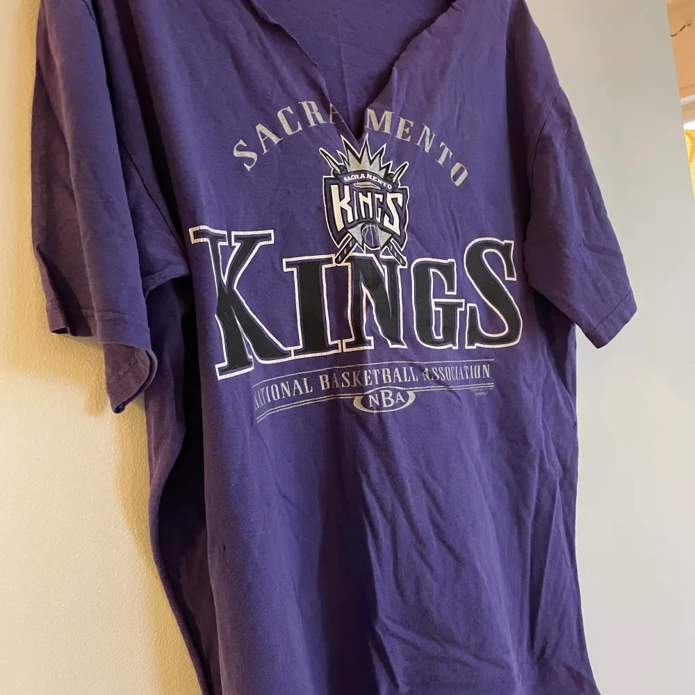 Retro baskettisha med ”KINGS” på. Kragen runt halsen är avklippt, samt en slits klippta på varje sida av tishan (se bild två). . T-shirts.