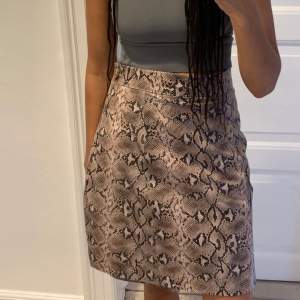 Snakeprint wrap-around skirt in leather with button closure on side