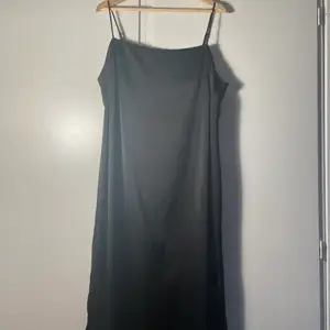 Black satin midi-length slip dress. Adjustable straps.