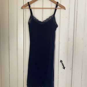 Slinkig mörkblå klänning (kort!) - Strl S, kort i fint skick. Knappt använd. Slinkigt tyg med spets upptill och längst ner